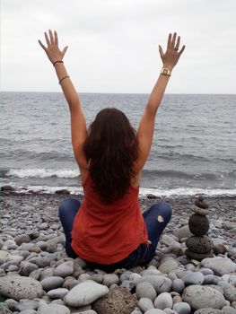 girl stretching arms in pebble beach in Madeira island, Portugal.