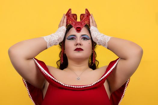 View of pinup vintage girl holding a red fantasy crown over a yellow background.