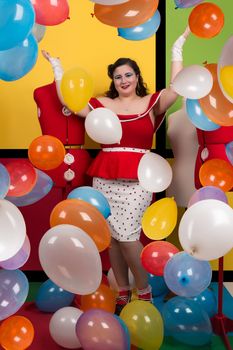 View of pinup vintage girl on a  colorful room filled with balloons.