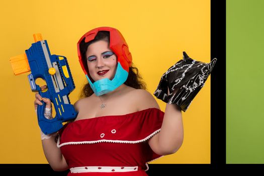 View of pinup vintage girl next to a colorful pop art background holding a nerf weapon.