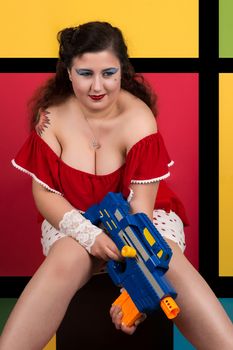 View of pinup vintage girl next to a colorful pop art background holding a nerf weapon.