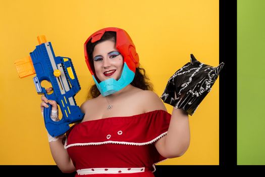 View of pinup vintage girl next to a colorful pop art background holding a nerf weapon.