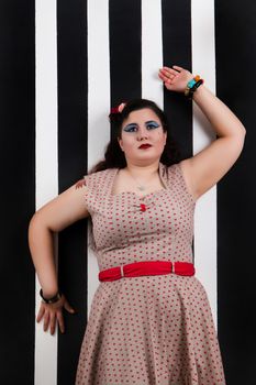 Pinup girl posing on a black and white stripes backdrop.