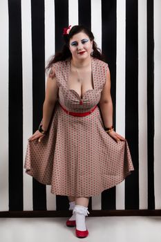 Pinup girl posing on a black and white stripes backdrop.