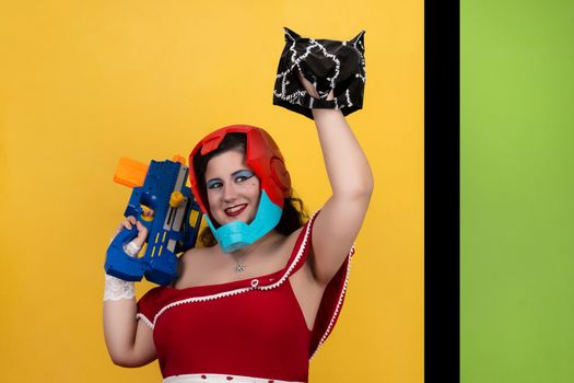 View of pinup vintage girl next to a colorful pop art background holding a nerf weapon.