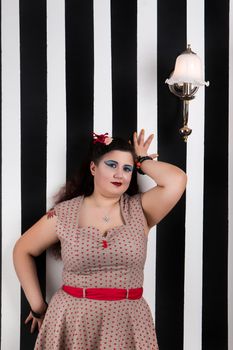 Pinup girl posing on a black and white stripes backdrop.