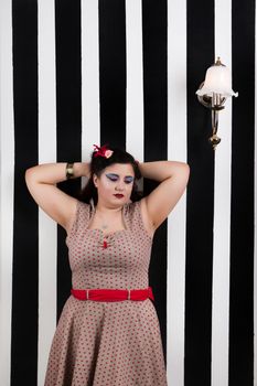 Pinup girl posing on a black and white stripes backdrop.