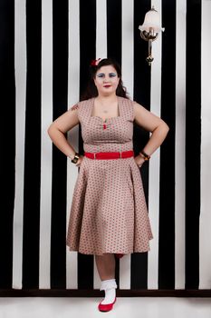 Pinup girl posing on a black and white stripes backdrop.