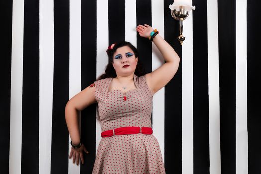 Pinup girl posing on a black and white stripes backdrop.