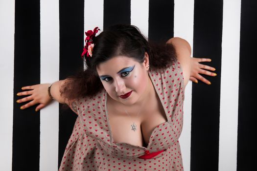 Pinup girl posing on a black and white stripes backdrop.