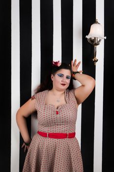 Pinup girl posing on a black and white stripes backdrop.