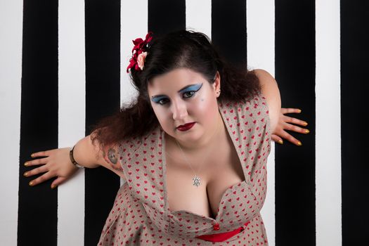 Pinup girl posing on a black and white stripes backdrop.