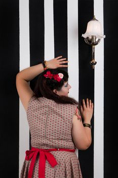 Pinup girl posing on a black and white stripes backdrop.