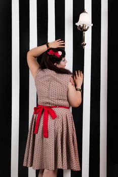 Pinup girl posing on a black and white stripes backdrop.