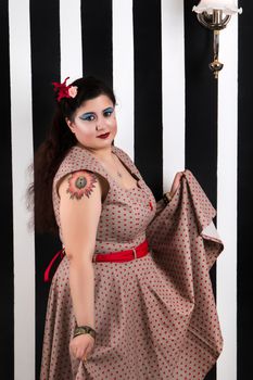 Pinup girl posing on a black and white stripes backdrop.