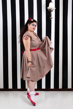 Pinup girl posing on a black and white stripes backdrop.