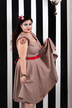 Pinup girl posing on a black and white stripes backdrop.