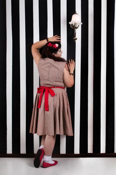 Pinup girl posing on a black and white stripes backdrop.