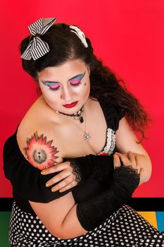 View of pinup vintage girl next to a colorfulred backdrop.