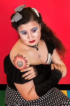 View of pinup vintage girl next to a colorfulred backdrop.