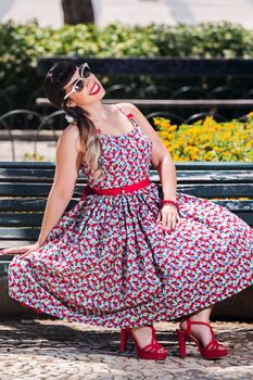 Pinup girl  with dress relaxing in the beautiful urban park.