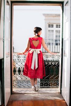 Pinup girl with red dress next to a classic window.