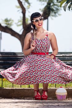 Pinup girl  with dress relaxing in the beautiful urban park.