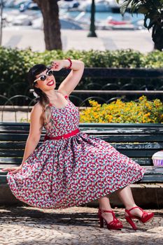 Pinup girl  with dress relaxing in the beautiful urban park.