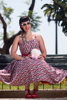 Pinup girl  with dress relaxing in the beautiful urban park.