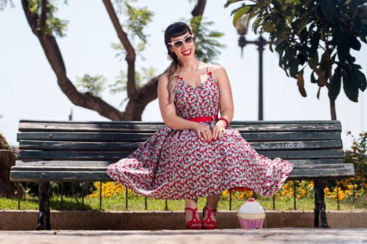 Pinup girl  with dress relaxing in the beautiful urban park.