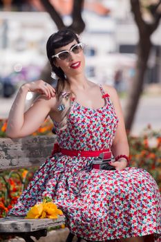 Pinup girl  with dress relaxing in the park, using a vintage camera.