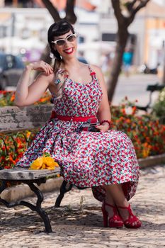 Pinup girl  with dress relaxing in the park, using a vintage camera.