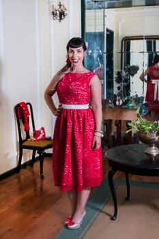 Pinup girl with red dress posing on a vintage home.