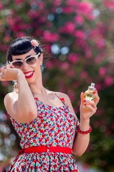 Pinup girl applying perfume in a beautiful urban park.