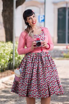 Pinup girl using a vintage camera in a urban park.