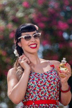 Pinup girl applying perfume in a beautiful urban park.