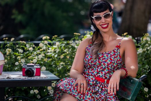 Pinup girl  with dress relaxing in the beautiful urban park.