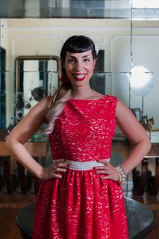 Pinup girl with red dress posing on a vintage home.