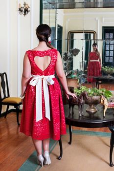 Pinup girl with red dress posing on a vintage home.