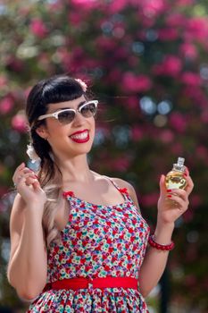 Pinup girl applying perfume in a beautiful urban park.