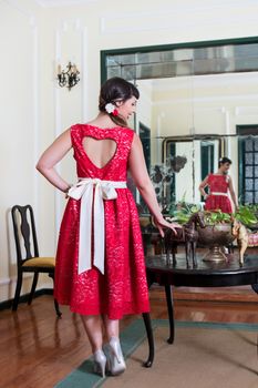 Pinup girl with red dress posing on a vintage home.