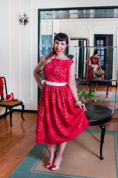 Pinup girl with red dress posing on a vintage home.