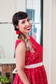 Pinup girl with red dress posing on a vintage home.