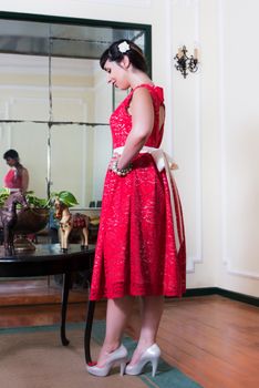 Pinup girl with red dress posing on a vintage home.