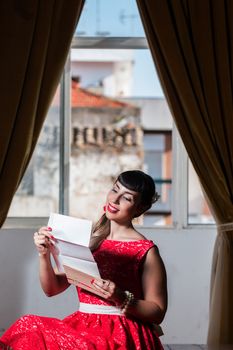 Pinup girl with red dress reading a romantic letter.