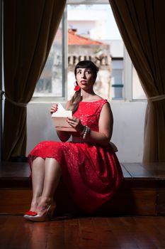 Pinup girl with red dress reading a romantic letter.