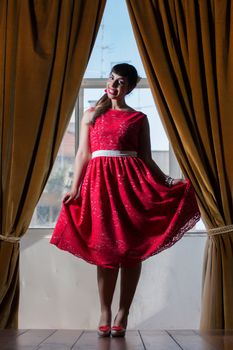 Pinup girl with red dress next to a classic window.