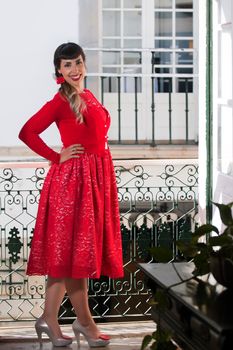 Pinup girl with red dress next to a classic window.