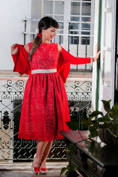 Pinup girl with red dress next to a classic window.