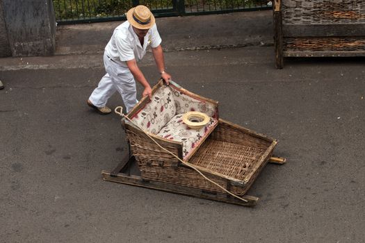 Traditional toboggan man operating a wicker basket car.